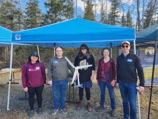 Five adults standing under a camping canopy tent