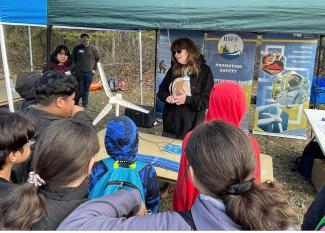 Maureen De Zeeuw standing behind a desk presenting to a group of children