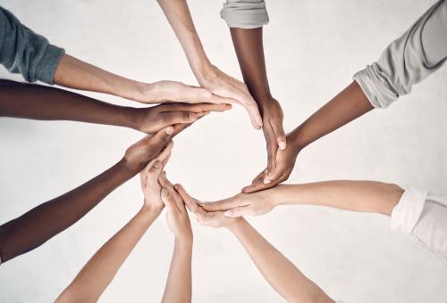 Hands from a diverse set of people making a circle shape.