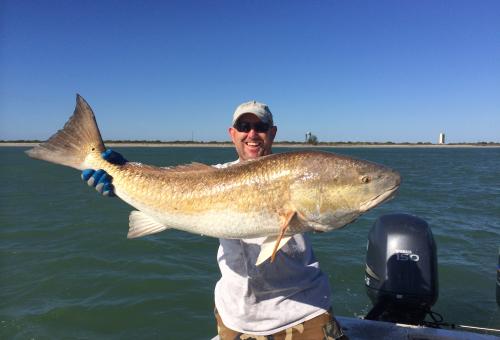 man holding red drum fish